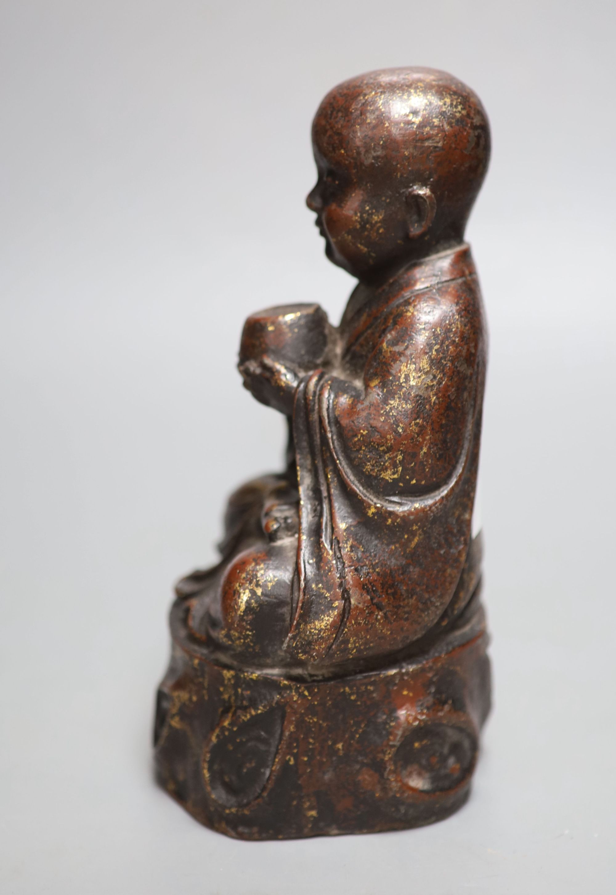 An Oriental patinated bronze seated youth, height 22cm